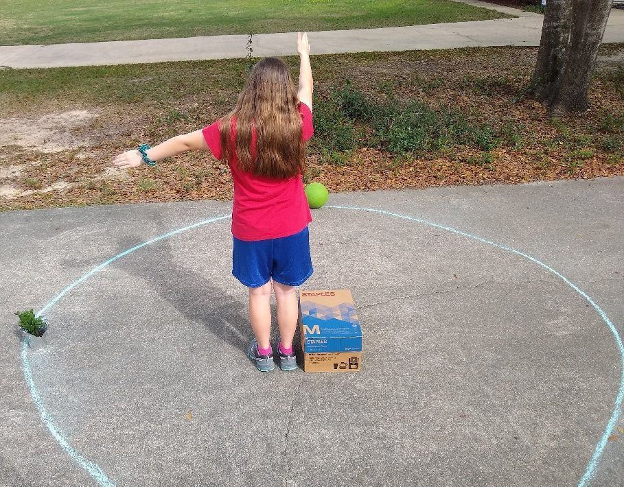Figure 26 A girl using her arms to show where the hour and minute hands would be pointing when the floral source is at the 9 o’clock position.