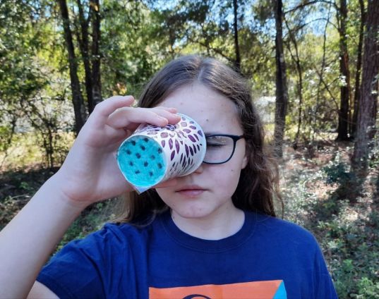 A girl trying out the Bee-noculars she made. 