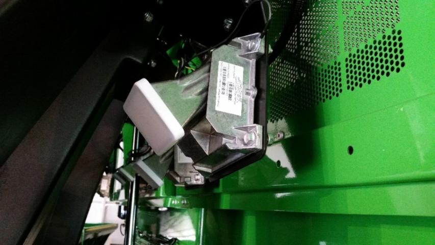 Figure 9. Microwave sensors covered in white casings and mounted behind the pneumatic ducts on a John Deere cotton picker.