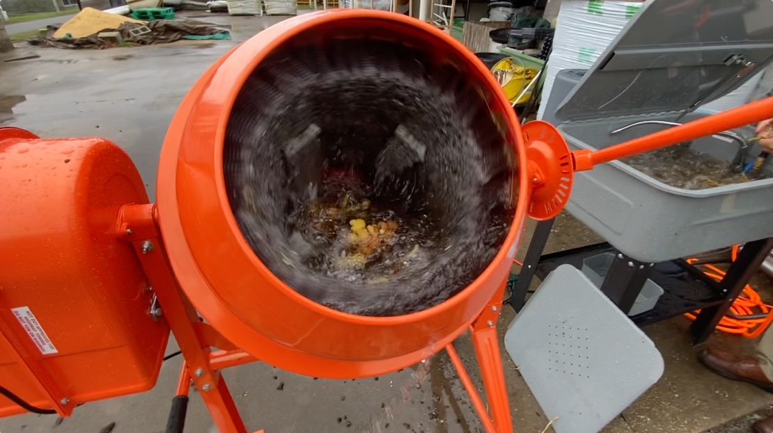 Water and rhizomes spinning inside uncovered barrel washer.