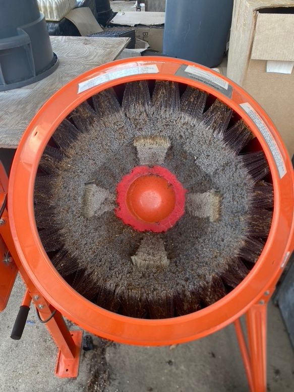 View looking into fully assembled barrel washer with open dome attached, where a small space exists at the center of the tub surronded by the lining of brushes and framed by the dome cover.