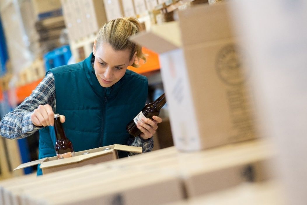 A brewery worker carefully inspects products during the packaging before shipment as part of the quality control process.