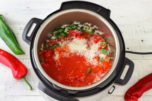 Open pressure cooker with red sauce and peppers and onions inside. 