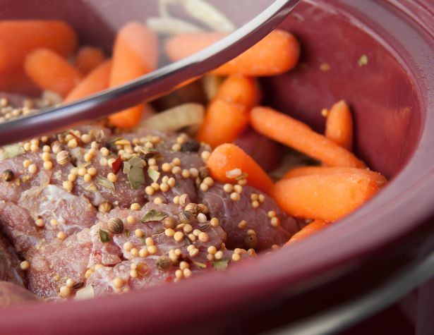 Image of a slow cooker with corned beef and carrots. 