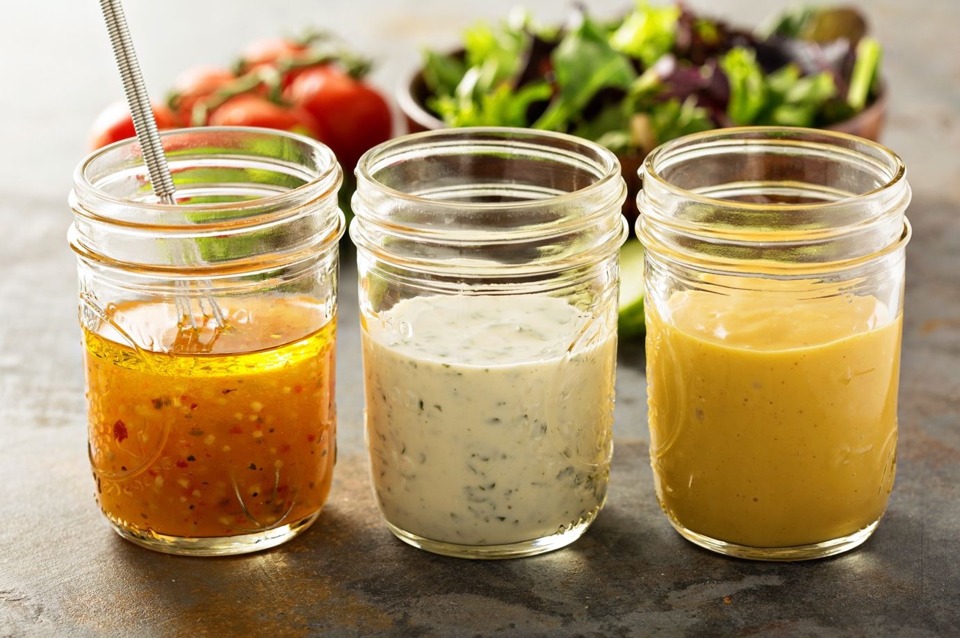 Variety of homemade sauces and salad dressings in mason jars including vinaigrette, ranch and honey mustard.