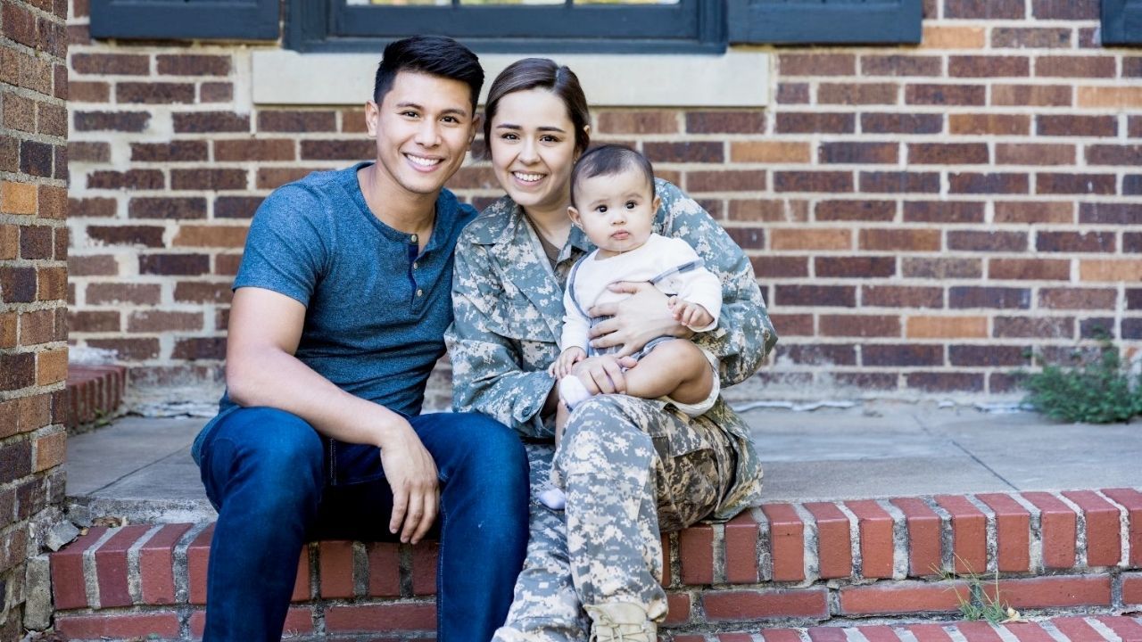 A person and person in military uniform sitting on steps with a baby

Description automatically generated