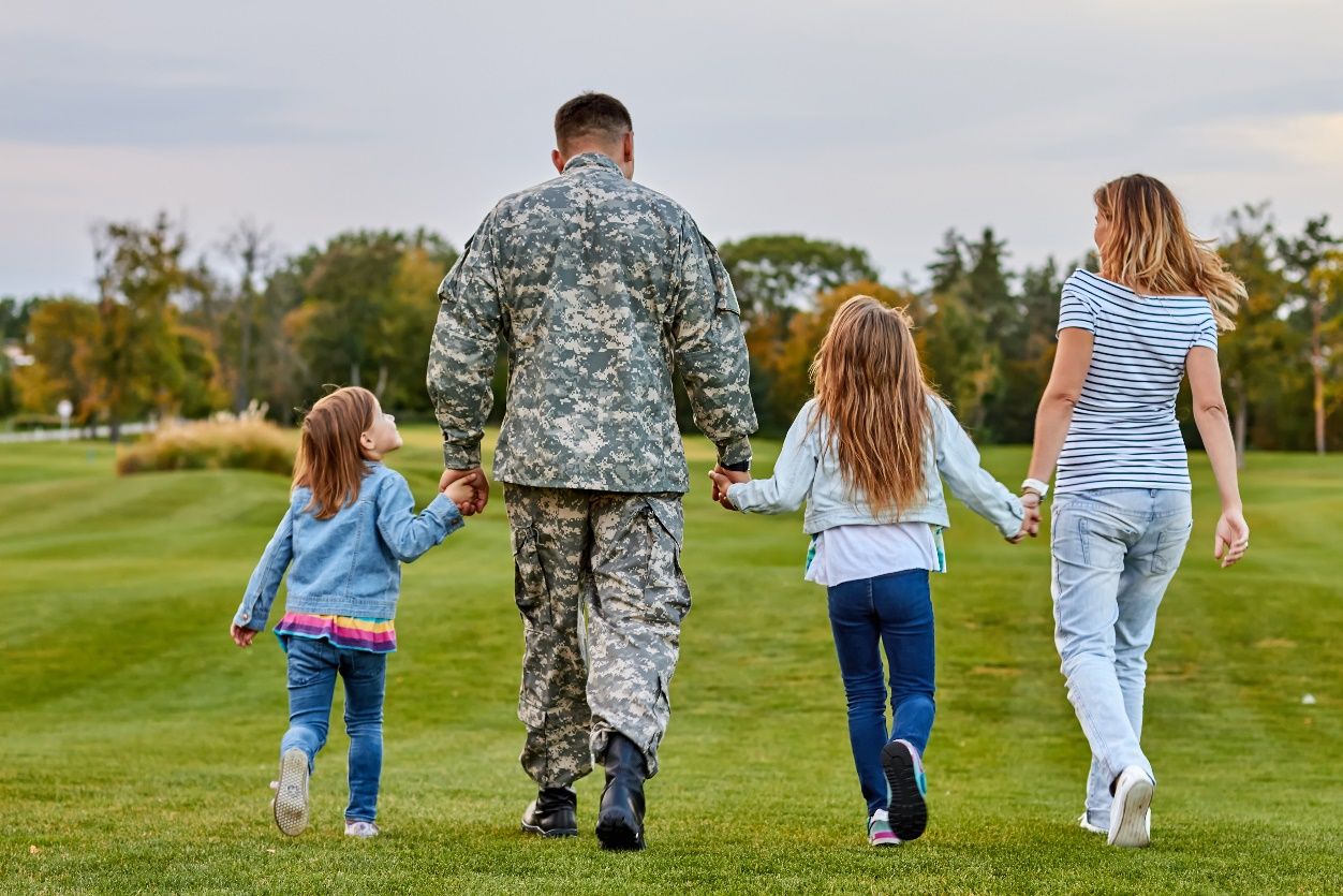 A person in military uniform holding hands with two children

Description automatically generated