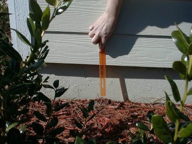 The building code requires at least a 6 inch inspection gap, as shown in the picture above. The inspection gap between mulch and siding on the home will allow anyone to see if termites are building mud tubes into a structure.
