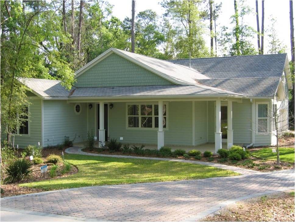 Another Gainesville, Florida home with more natural landscaping. It has a small patch of lawn, a natural landscaped rain garden, conserved trees, and a permeable paved driveway. 