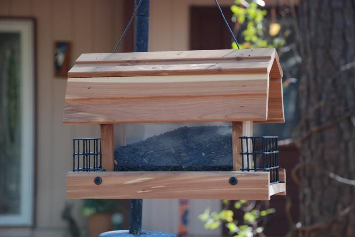 un comedero de tolva sostenido por alambre en el patio de una casa.