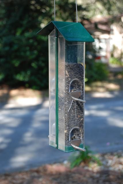 un comedero de tubo  techo de plástico con un techo de color verde asimilando la imagen de una casa llena de semillas