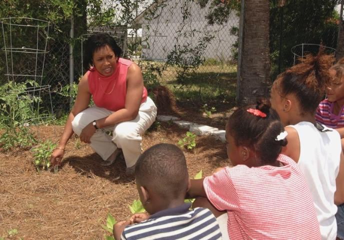 Figure 1. Children with extension agent learning about planting gardens.