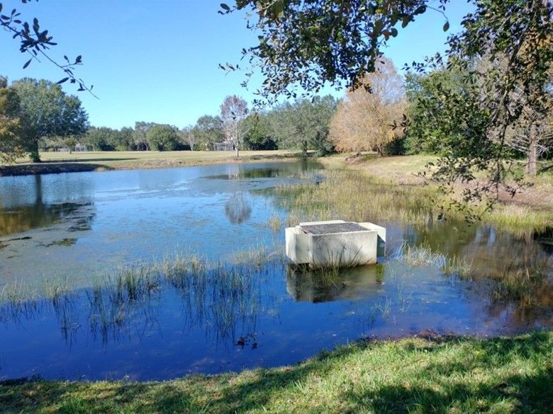 The concrete structure shown is an overflow structure designed to keep water below a certain level by diverting excess water to other nearby water bodies to prevent flooding. The presence of this structure indicates the water body is a stormwater pond. 