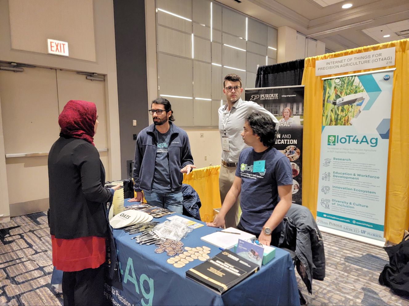 Research assistants (left to right) Fabio, Justin, and Sami speaking with a visitor at the IoT4Ag Center booth at MANRRS 2024.